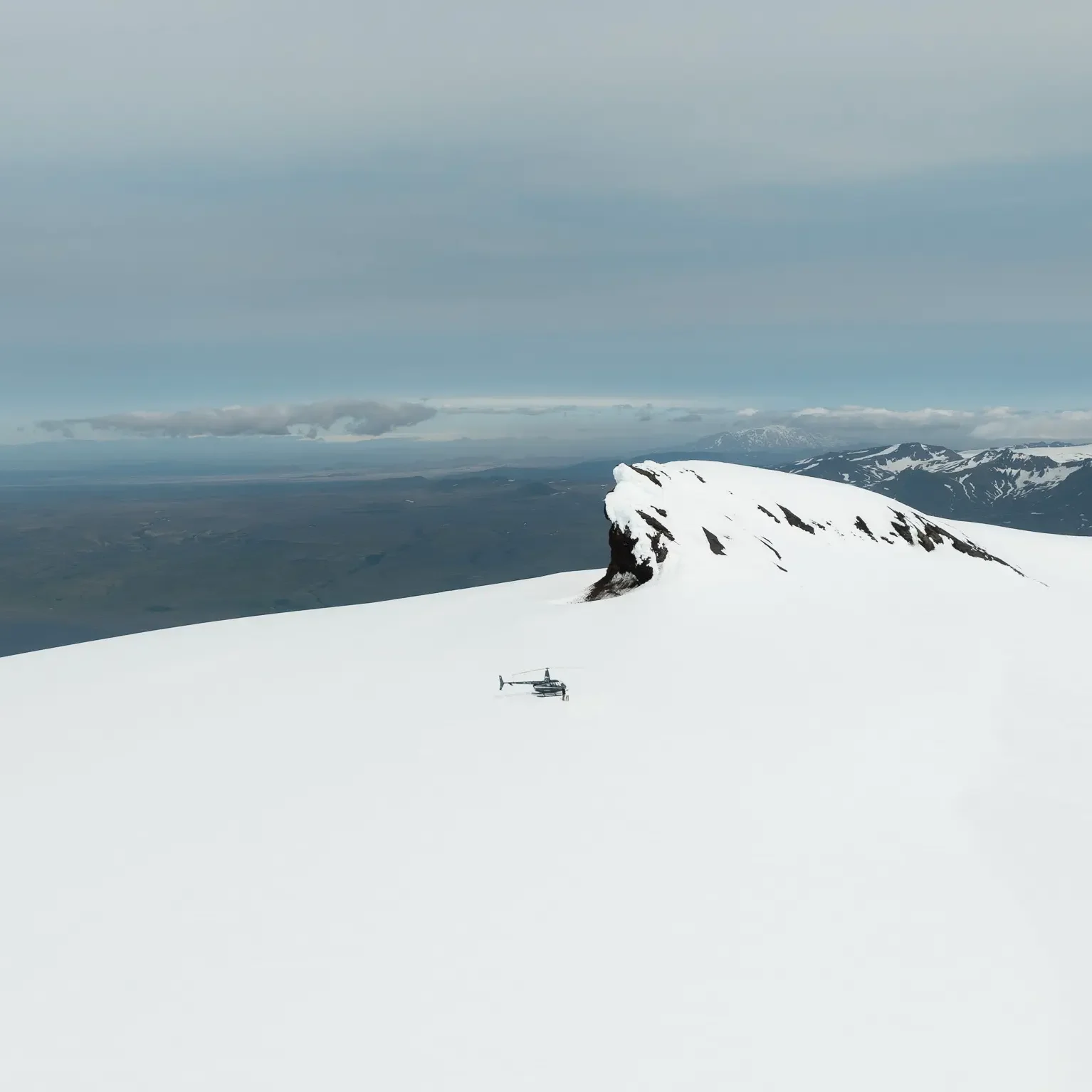 Helicopter landing on a glacier during an Iceland elopement, surrounded by snowy mountains