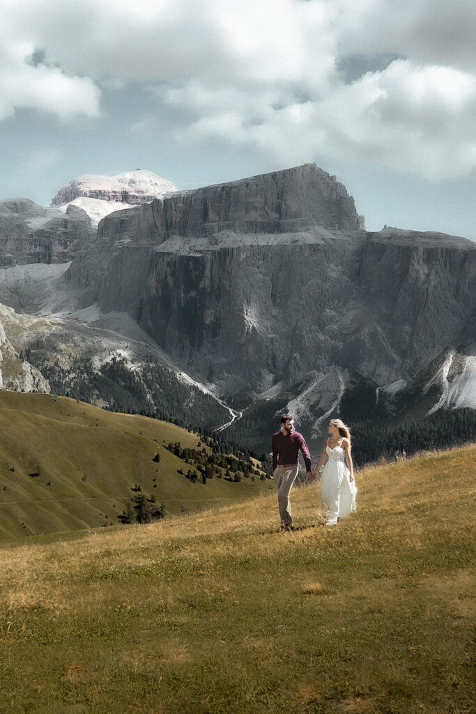 Elopement couple walking in the Dolomites on a mountain meadow