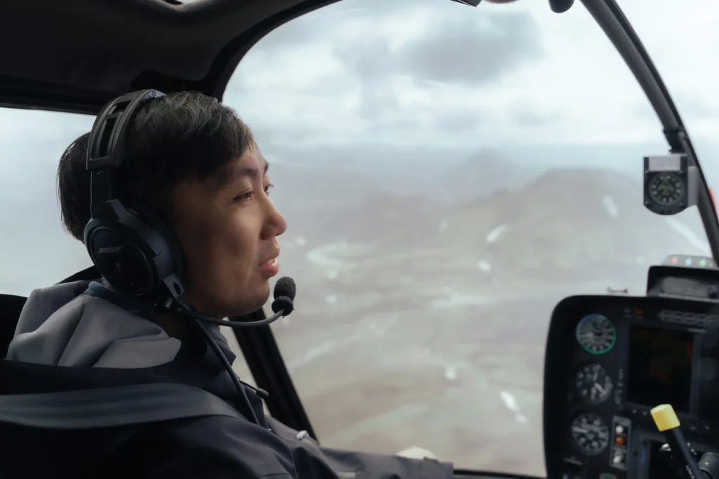 Engaged man wearing a headset inside a helicopter flying over the rugged Icelandic highlands of Landmannalaugar.