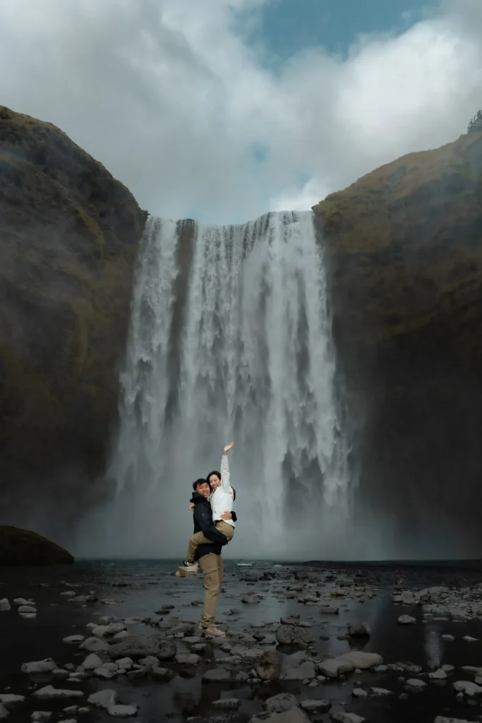 Couple embracing during an engagement photoshoot at Skogafoss waterfall in Iceland.