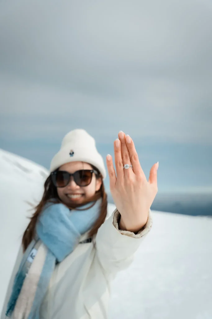 A woman showing her engagement ring while standing on a snowy glacier in Iceland.