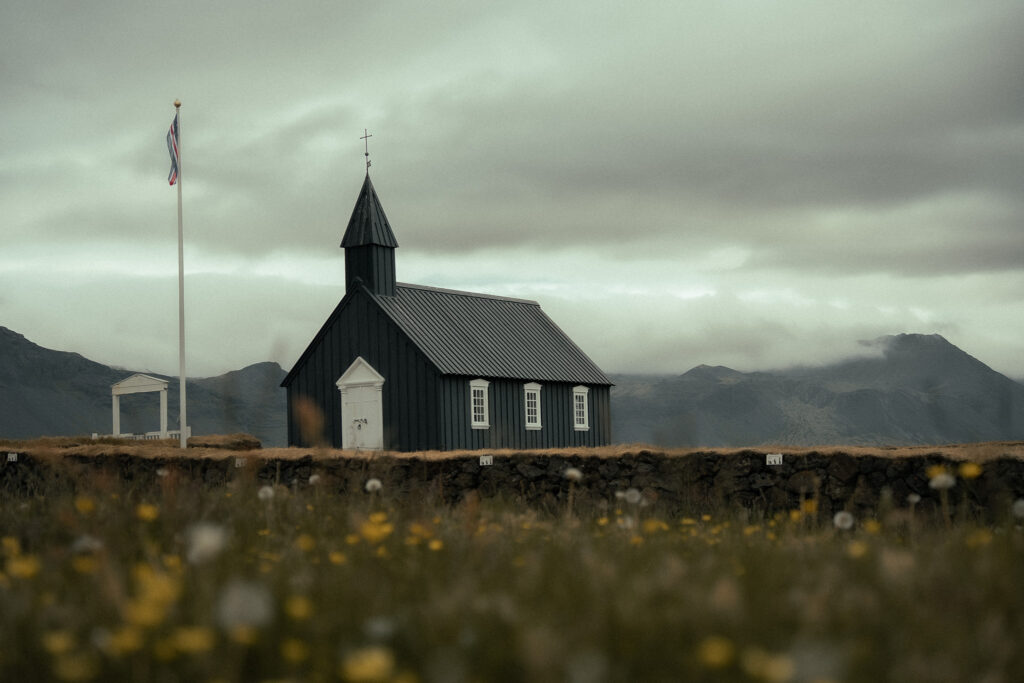 The iconic black wooden church of Búðakirkja standing alone in a quiet Icelandic landscape