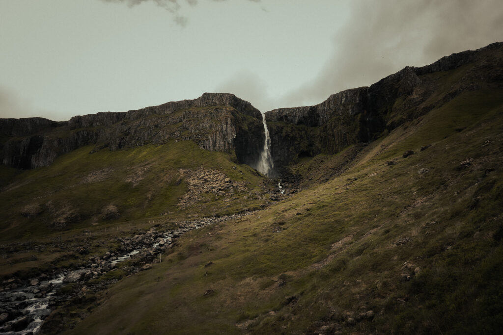 Grundarfoss waterfall in Iceland flowing down a steep cliff into a green valley