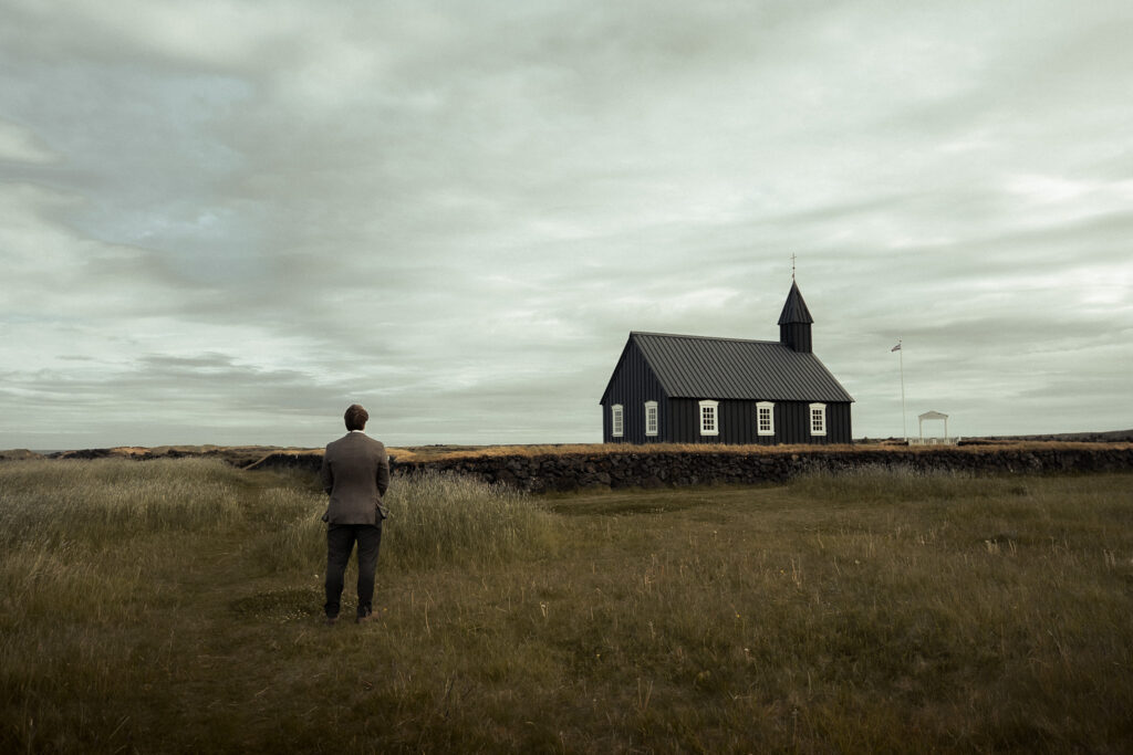 Groom waiting for his bride in front of the black church Búðakirkja in Iceland