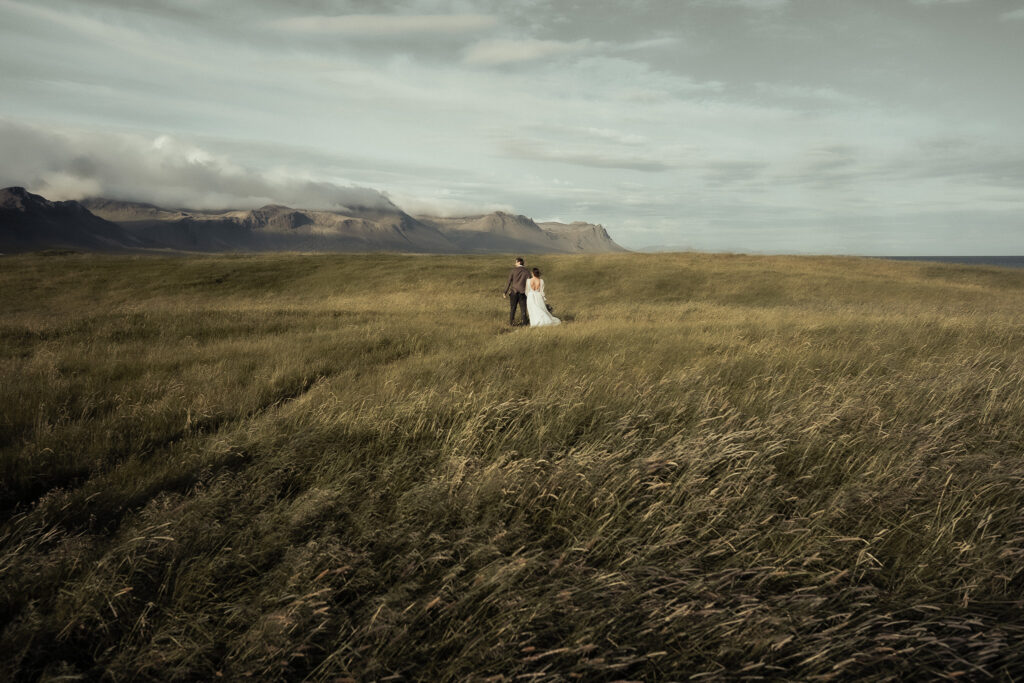 Elopement couple holding hands in a mountain meadow in Iceland during a destination wedding