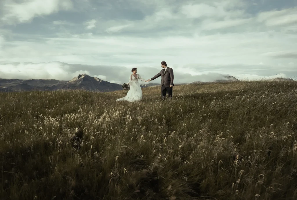 Elopement couple holding hands in a mountain meadow in Iceland during a destination wedding