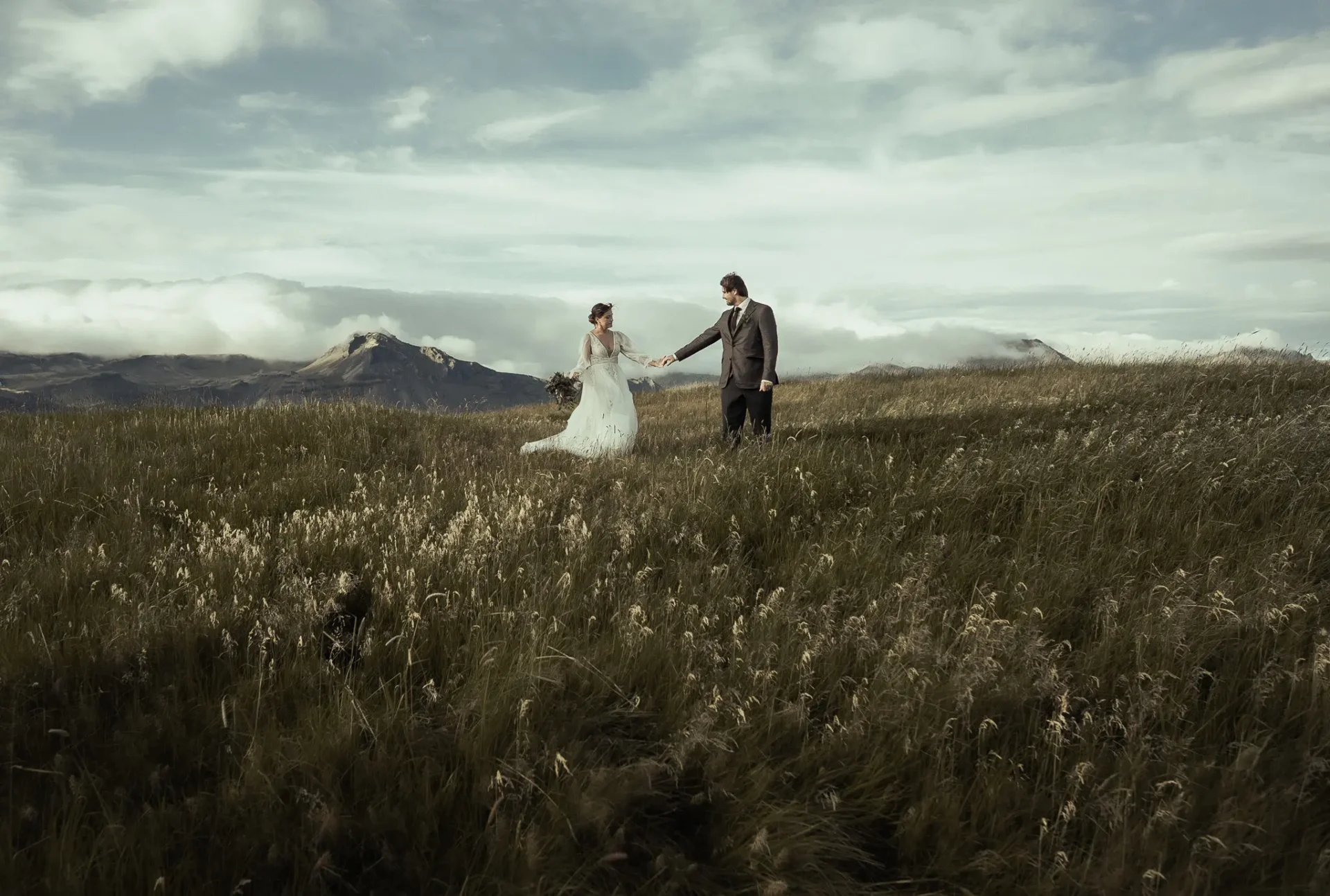 Elopement couple holding hands in a mountain meadow in Iceland during a destination wedding