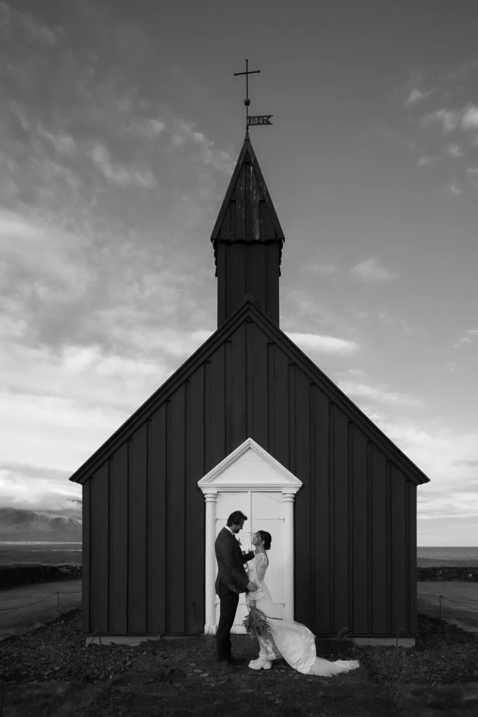 Couple standing in front of a black church in Iceland