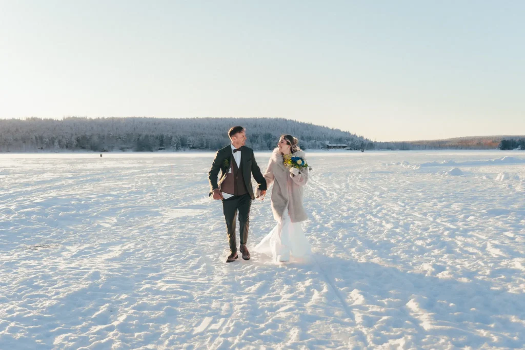 Wedding couple running across a frozen lake in Rovaniemi, Lapland
