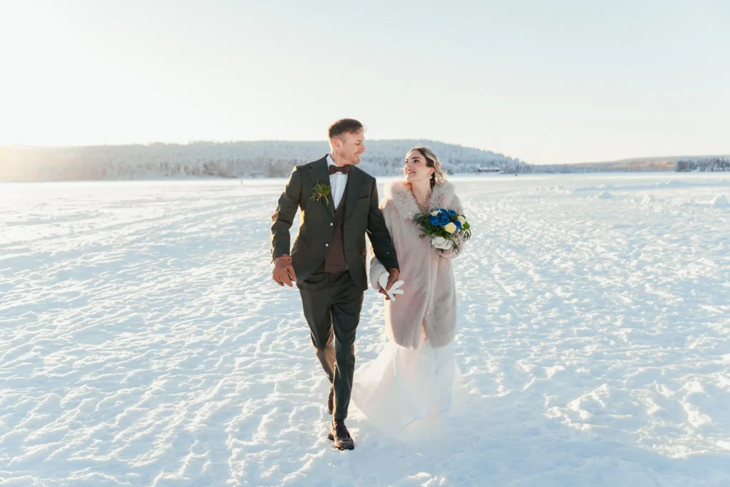 Wedding couple running across a frozen lake in Rovaniemi, Lapland