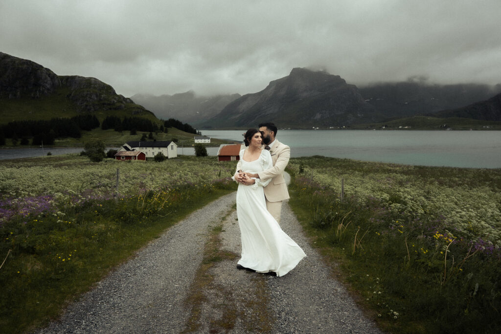 Elopement couple standing on a road with a fjord and mountains on the Lofoten Islands in Norway