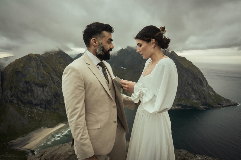 Bride reading her vows to the groom on a cliff above Kvalvika beach in the Lofoten Islands