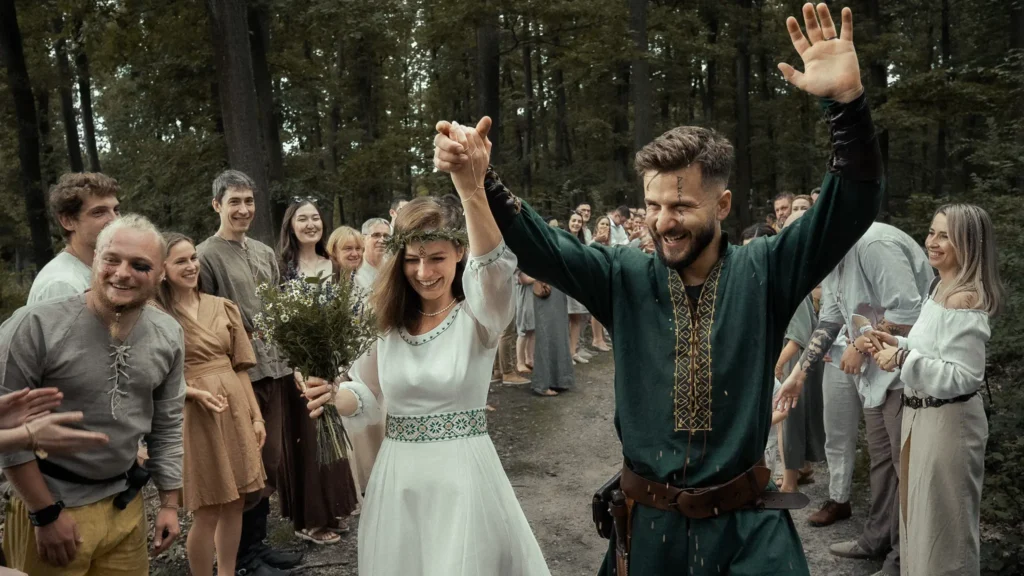 Bride and groom walking through guests in a forest during a pagan wedding ceremony