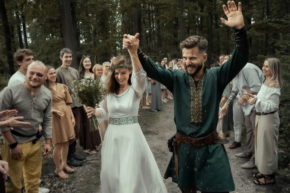 Bride and groom walking through guests in a forest during a pagan wedding ceremony