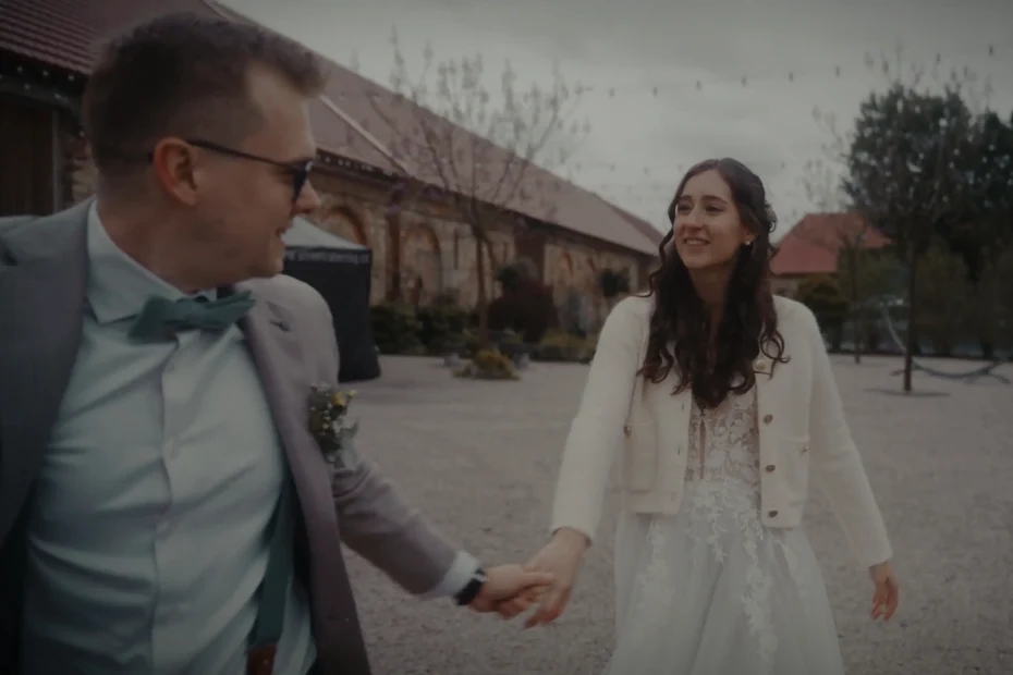 Nevěsta a ženich kráčejí ruku v ruce na nádvoří svatebního areálu