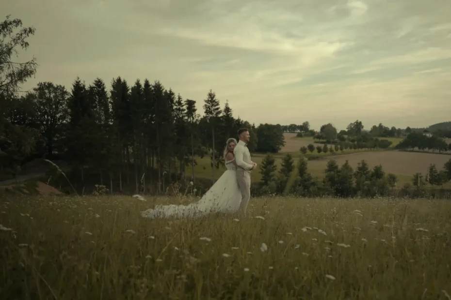 Nevěsta objímá ženicha zezadu uprostřed louky