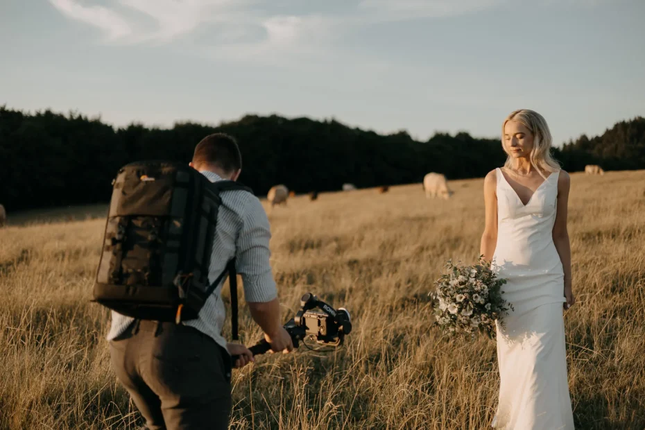 Svatební kameraman natáčí nevěstu při západu slunce na poli